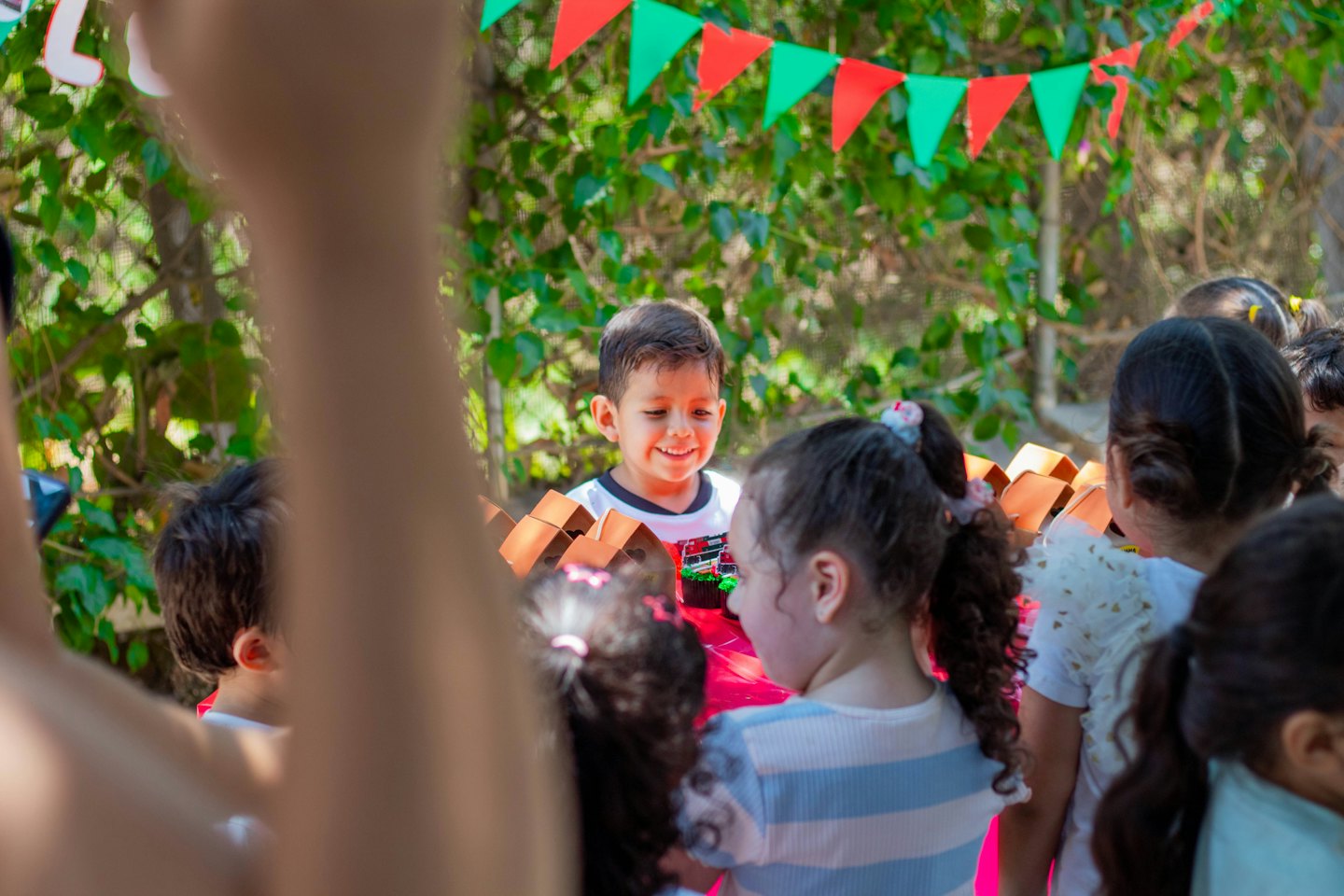 A boy smiles while standing with friends at an outdoor party.