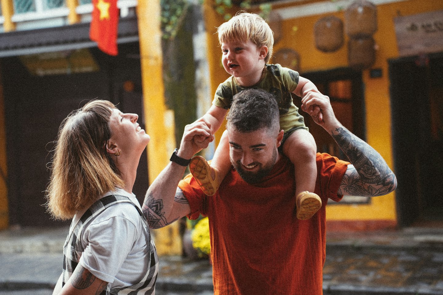 Family walking together on a street with a child on shoulders.